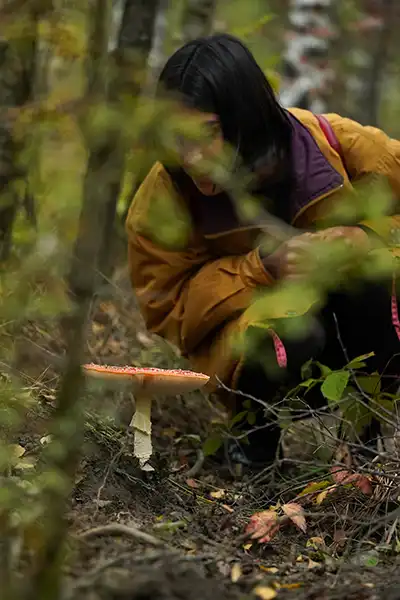 Deelnemer bekijkt van dichtbij een vliegenzwam in het bos