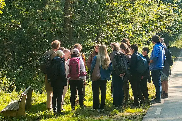 Groep wandelaars luistert op een zonnig bospad